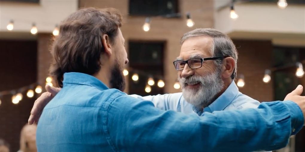 En ældre og yngre mand kommer smilende hinanden i møde