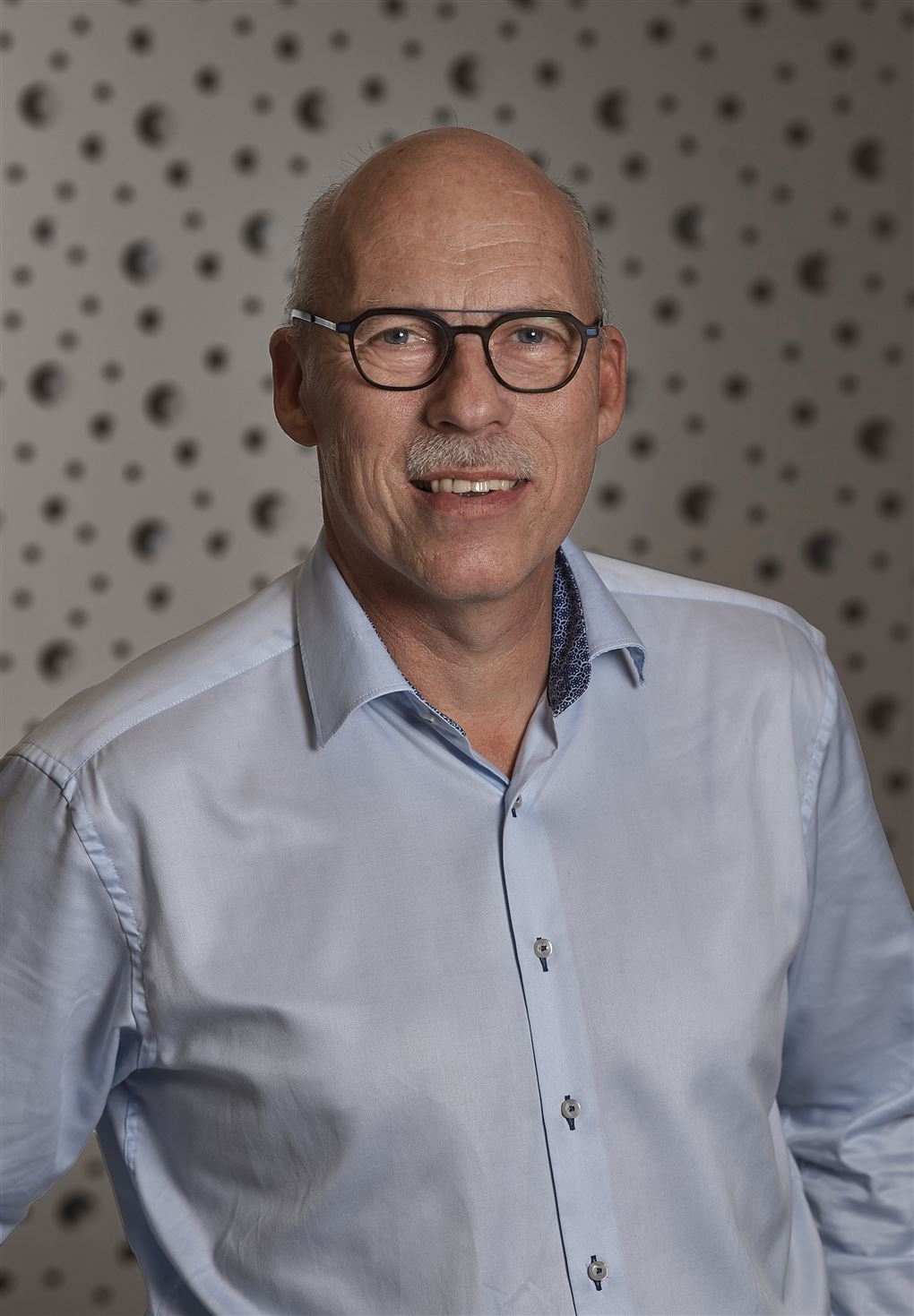 En mand med overskæg smiler