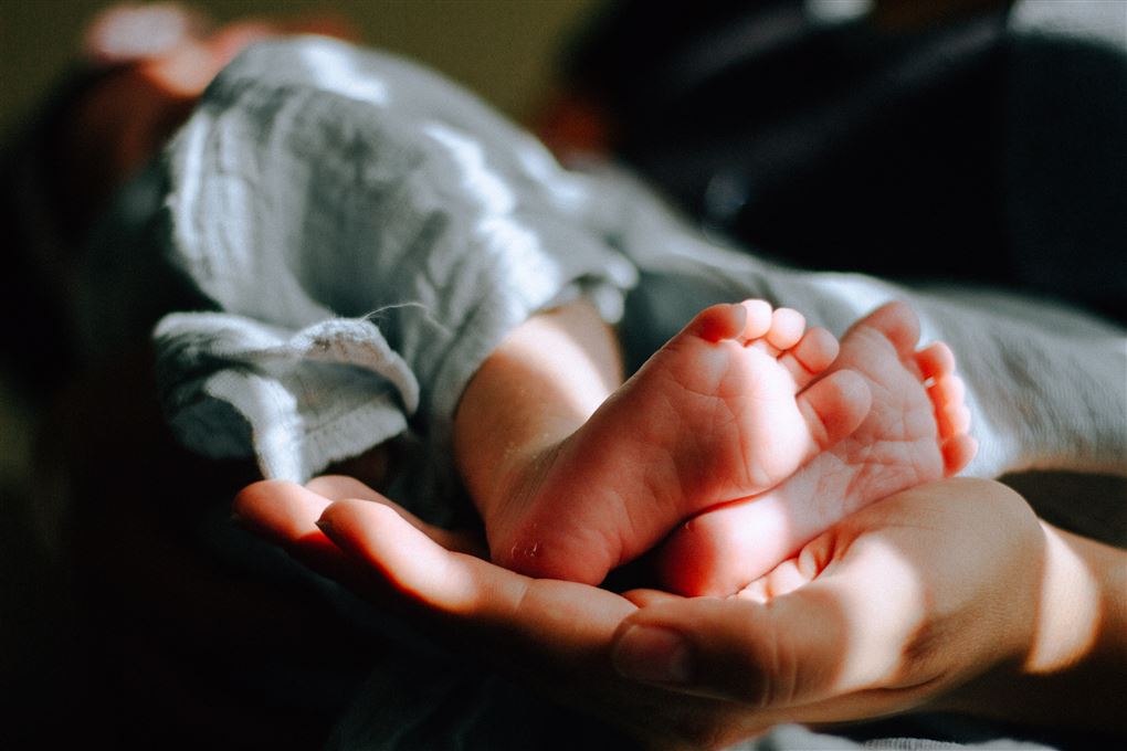 En hånd støtter to små babyfødder.