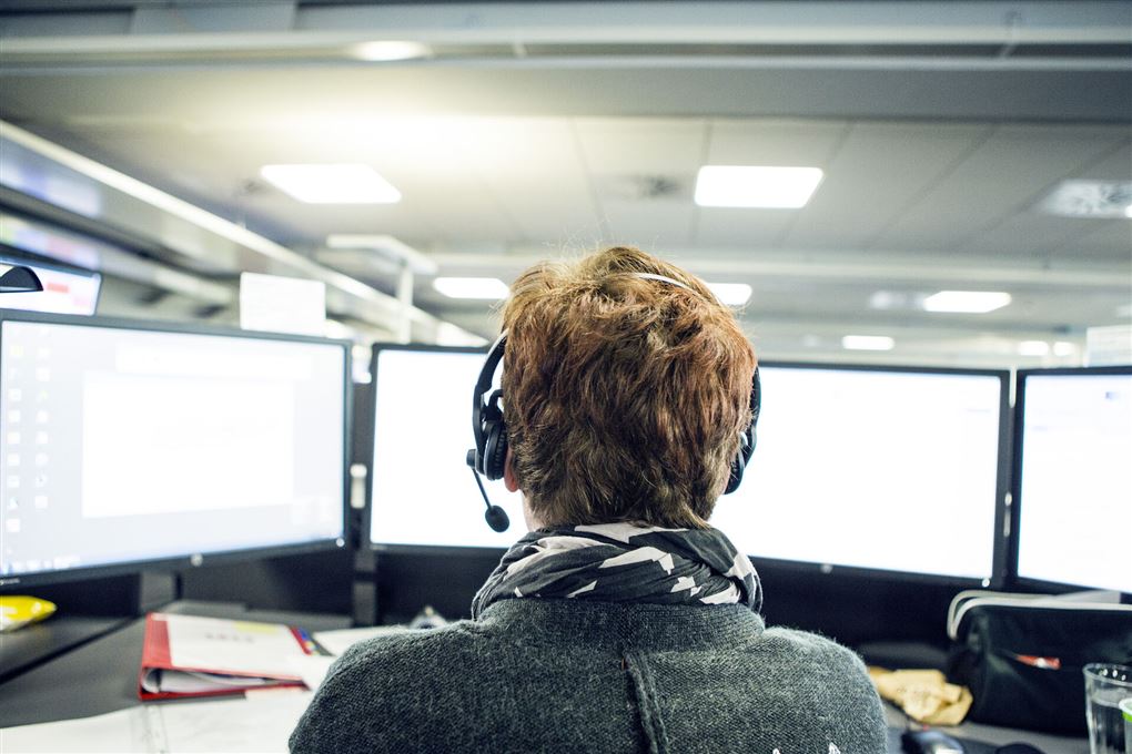 Kvinde med headset foran skærme