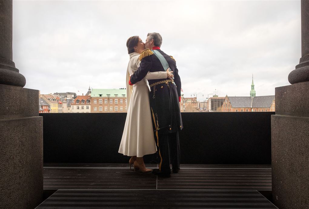 Et kongepar kysser på en balkon