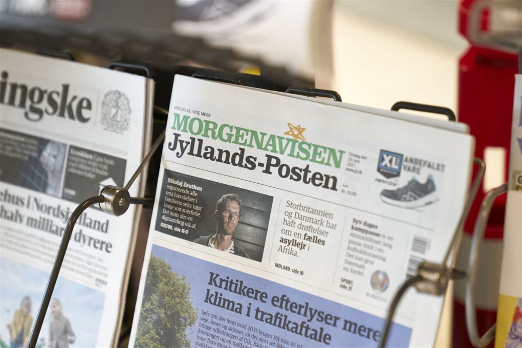 Jyllands Posten står ved siden af Berlingske i et avisstativ.