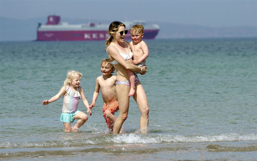 en kvinde og børn i strandkanten
