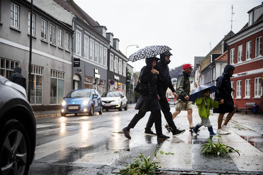 Personer med paraplyer på regnvåd gade