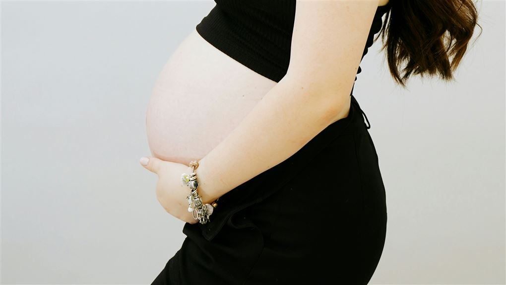 En gravid mave og en kvinde som holder på den.