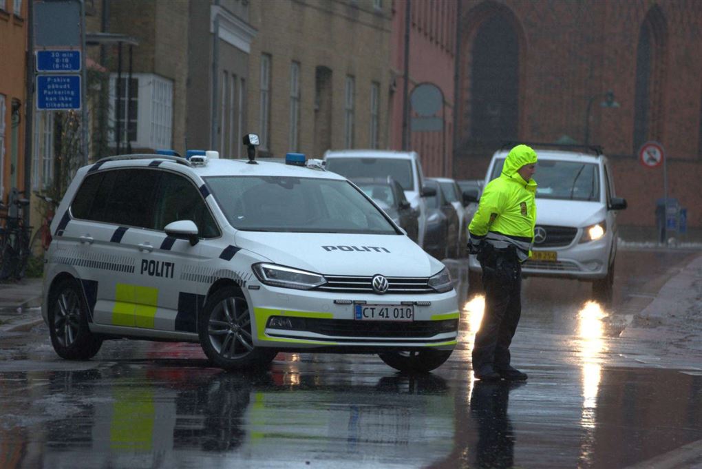 politi og politibiler i regnfuld gade