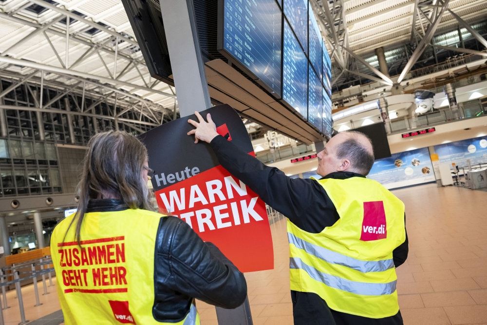 personer i gule veste hænger skilte op