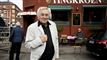 Mand i lys jakke foran facaden en bygning