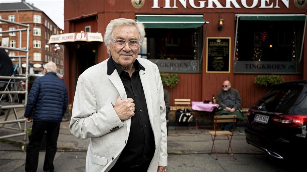 Mand i lys jakke foran facaden en bygning