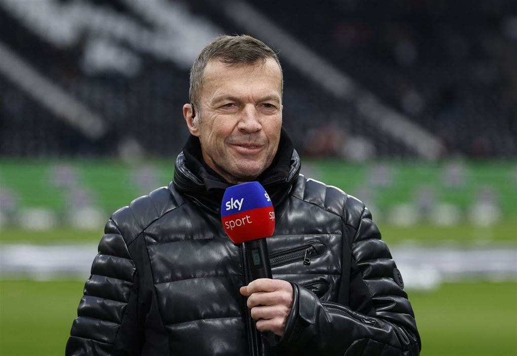 Mand i dunjakke på fodboldstadion holdende en mikrofon