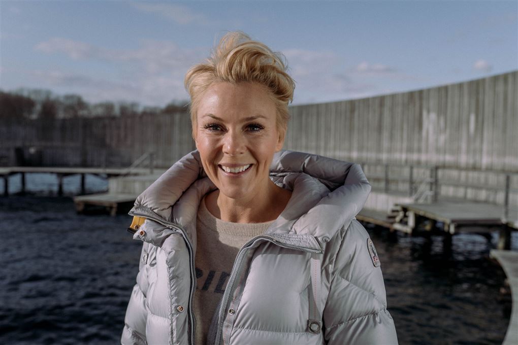 Smilende kvinde i dunjakke ved havnebad