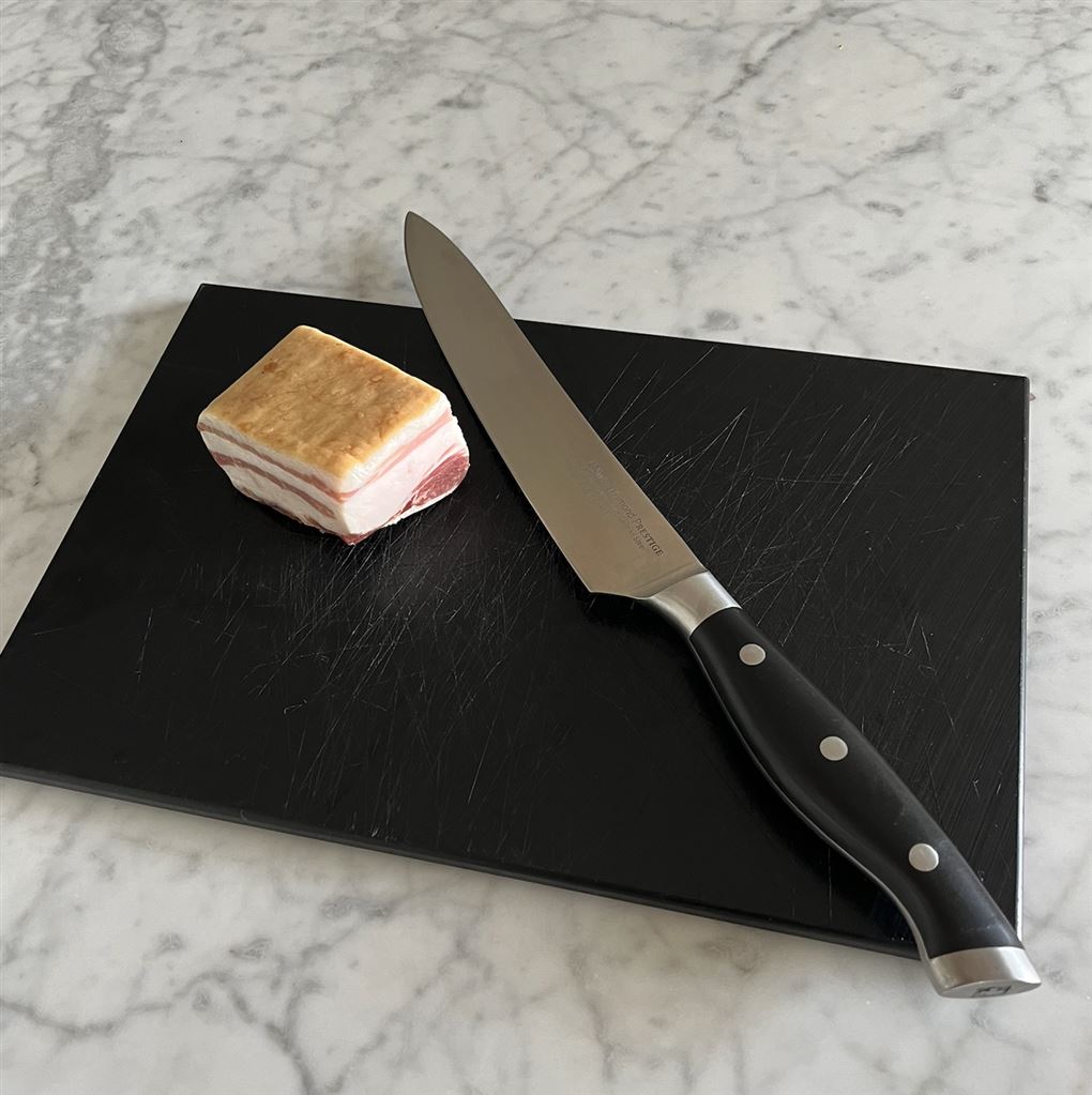 en kniv og et stykke bacon på bordet