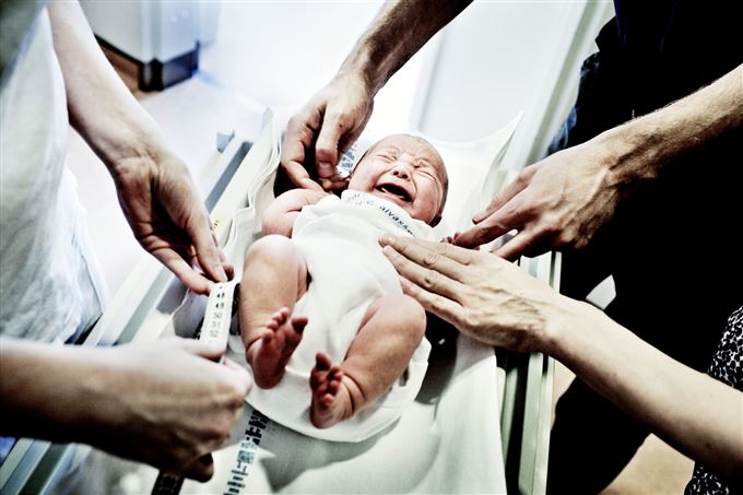 En nyfødt baby bliver målt og vejet
