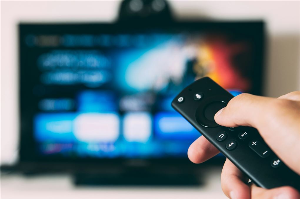 Tryk på fjernbetjening med TV i baggrunden