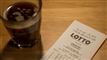 Lottokupon og glas med kaffe på bord