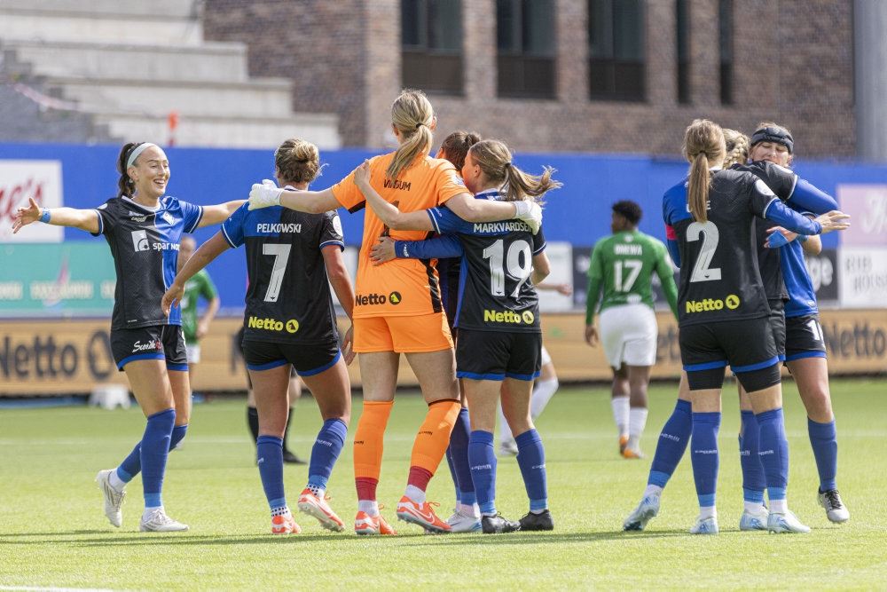 En masse fodboldkvinder omfavner hinanden