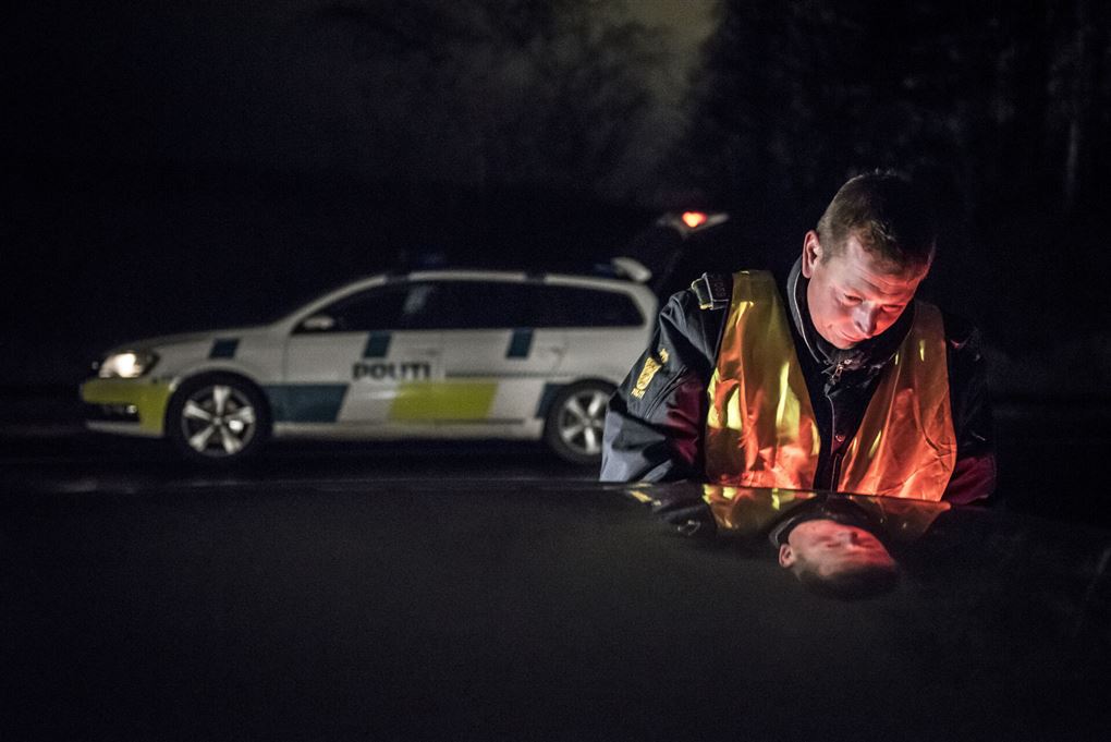 politibetjent står ved bil 