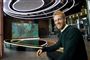 Mand sidder ved et skrivebord i et tv-studie