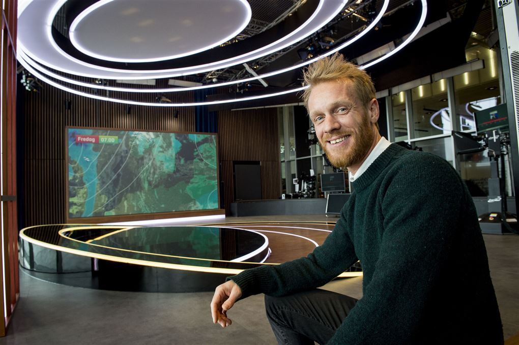 Mand sidder ved et skrivebord i et tv-studie
