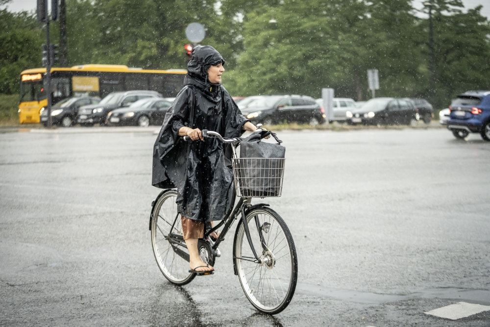 Kvinde på cykel i regnvejr