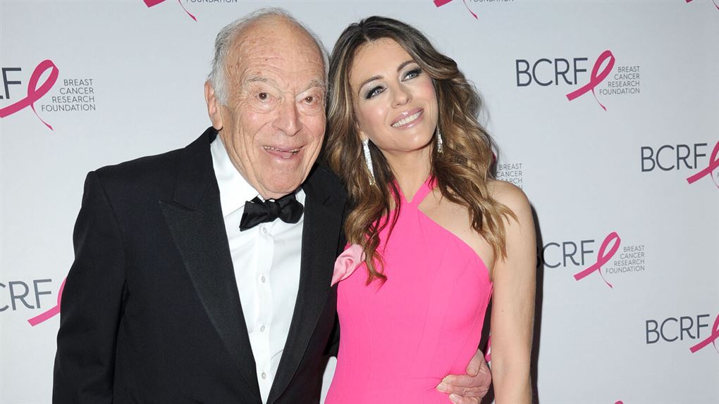 Leonard Lauder i smoking med armene om Elizabeth Hurley i pink kjole
