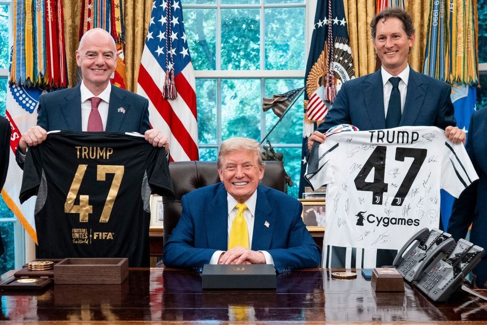 Trump smiler mens to mænd fremviser fodboldtrøjer