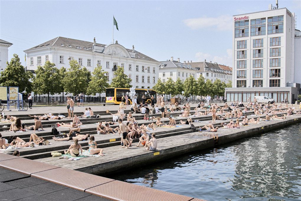 En masse mennesker ligger og soler sig ved kanalen 