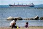 folk på strand med skib i baggrunden