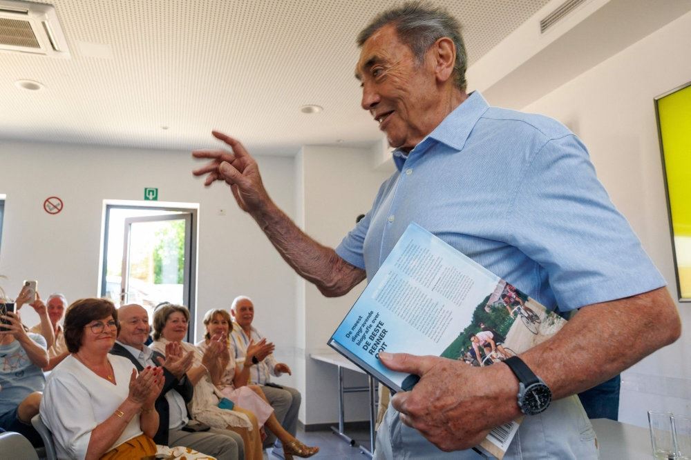 Mend med bog i håndende foran publikum