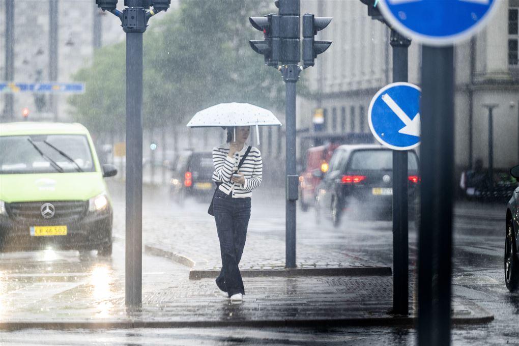Kvinde med paraply på gade i regnvejr