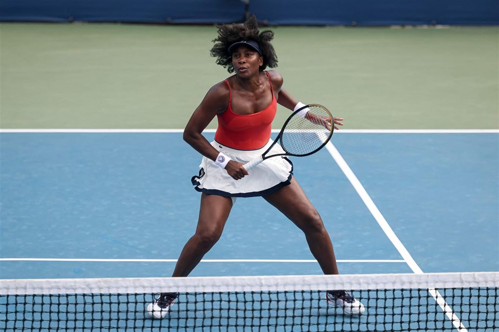 Venus Williams i rød top og hvid underdel på tennisbanen