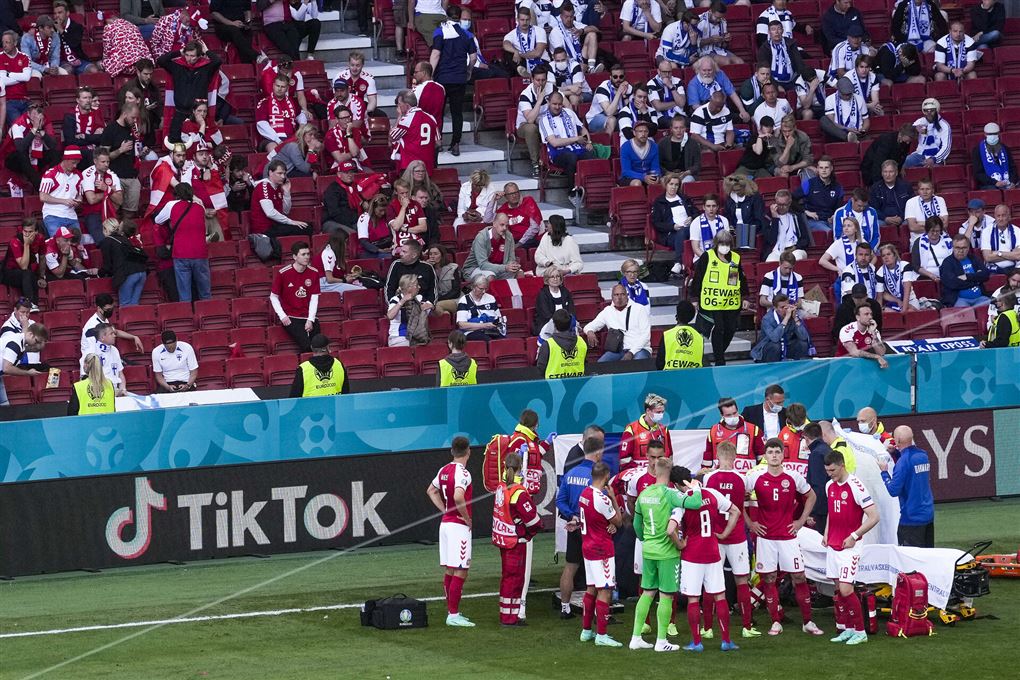 fodboldspillere danner ring på banen efter en spiller er kollapset
