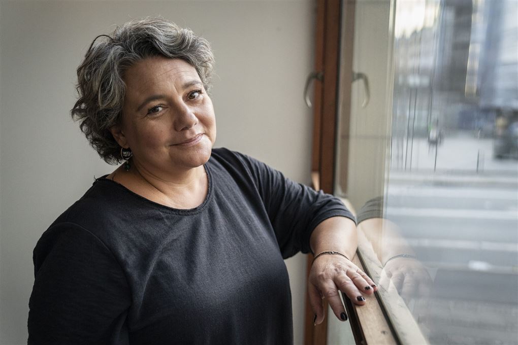 Anne Herdorf står med armen op ad en vindueskarm og smiler til kameraet