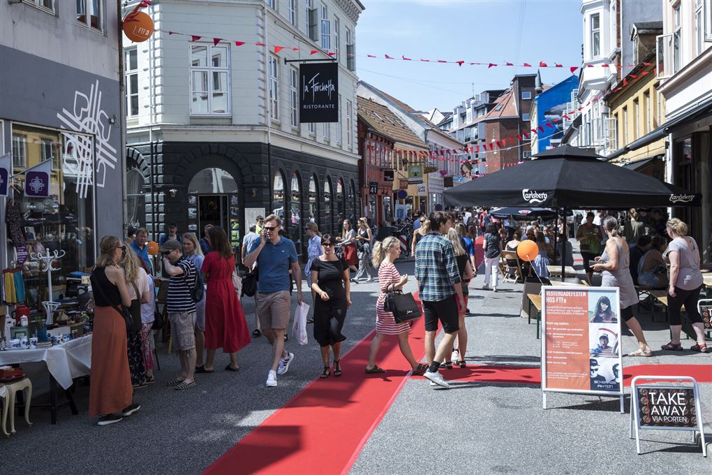 En gade med røde løbere på midten af vejen og en masse mennesker, der kigger på boder
